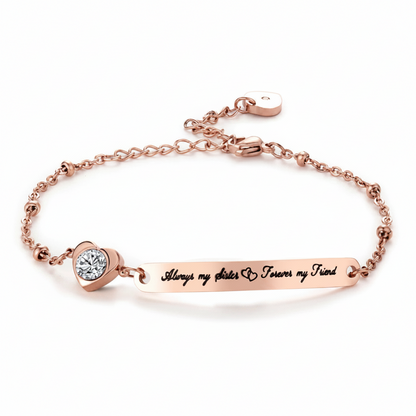 Rose gold bracelet featuring a horizontal bar engraved with 'Always my sister & forever my friend' and a heart-shaped bezel-set clear stone, shown on a white background.