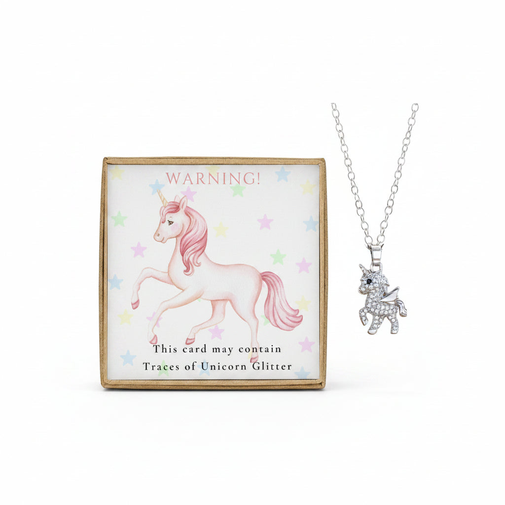 A stainless steel unicorn pendant necklace with a gold foiled box and a warning card that says 'This card may contain traces of Unicorn Glitter'.