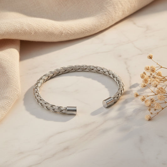 A silver braided cuff bracelet with polished metal end caps, displayed on a clean white background.
