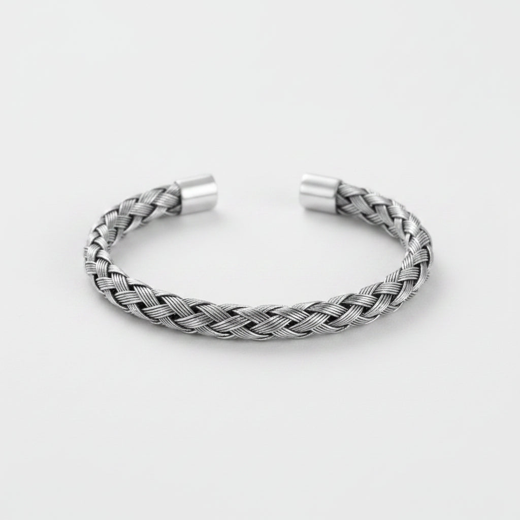 A silver braided cuff bracelet with a textured woven pattern and polished metal end caps, displayed on a clean light gray background.