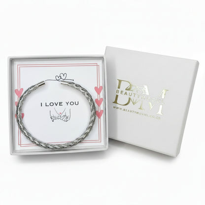 A silver-toned twisted wire bracelet presented in an open white gift box with a printed card that says 'I LOVE YOU,' next to the closed branded box on a white background.
