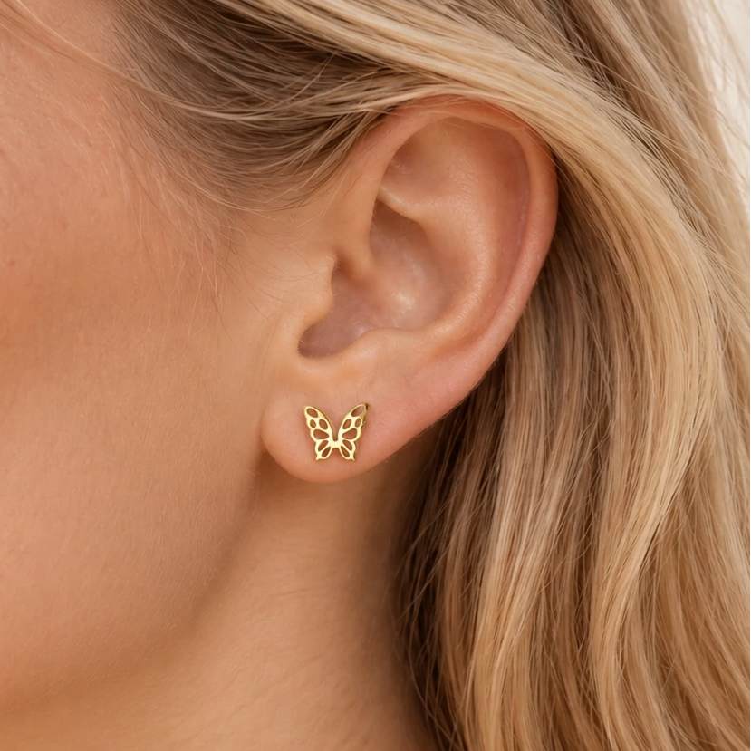 Close-up of a model wearing a dainty gold-tone openwork butterfly stud earring