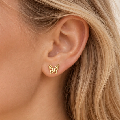 Close-up of a model wearing a dainty gold-tone openwork butterfly stud earring