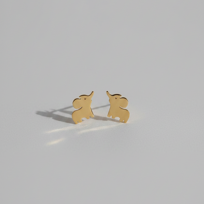 A pair of small gold elephant stud earrings on a plain light gray background.