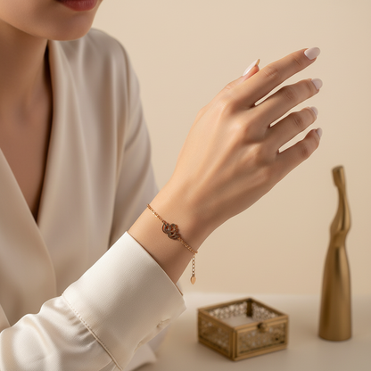 beautymogul rose gold chain bracelet -A close-up of a woman's hand wearing a delicate rose gold chain bracelet with a clover motif, styled with a cream blouse and a neutral beige background.