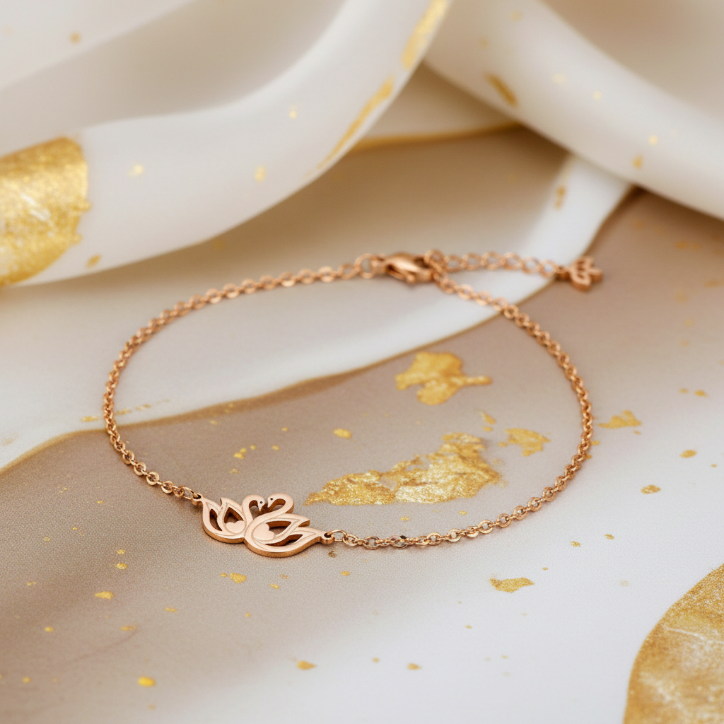 A delicate beautymogul rose gold chain bracelet with a swan cutout charm, displayed on a styled background of white and gold marbled paper.